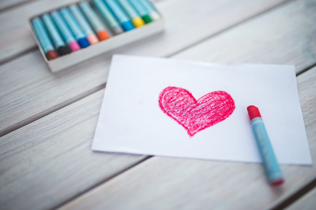 a heart drawing with pastel crayons next to it