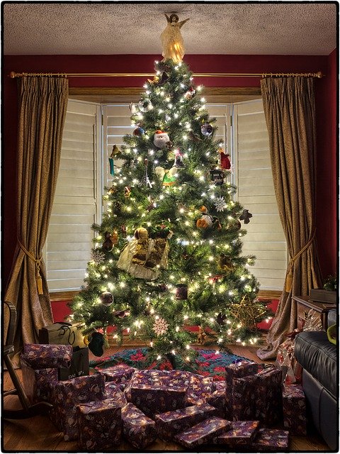 A Christmas tree touching the ceiling in a living room