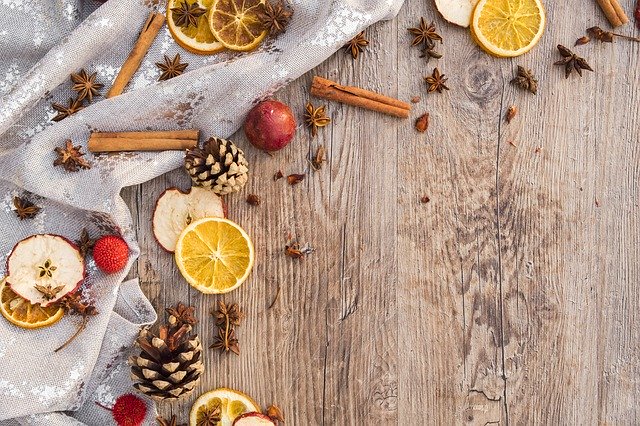 Cinnamon sticks, pinecones and fruits scattered at wooden floor