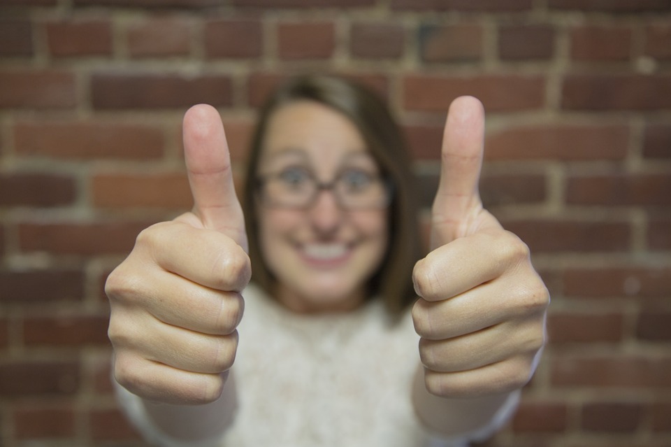 A girl showing thumbs up because she knows the best strategies for helping your teenager deal with a major relocation.