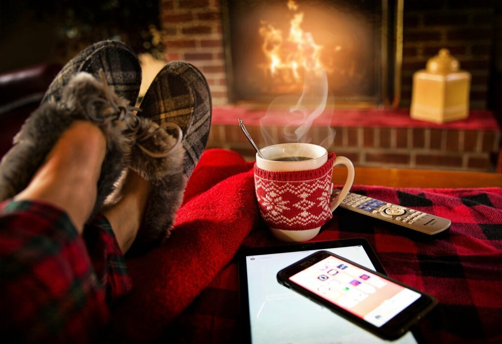 Man in front of a fireplace on a sofa.