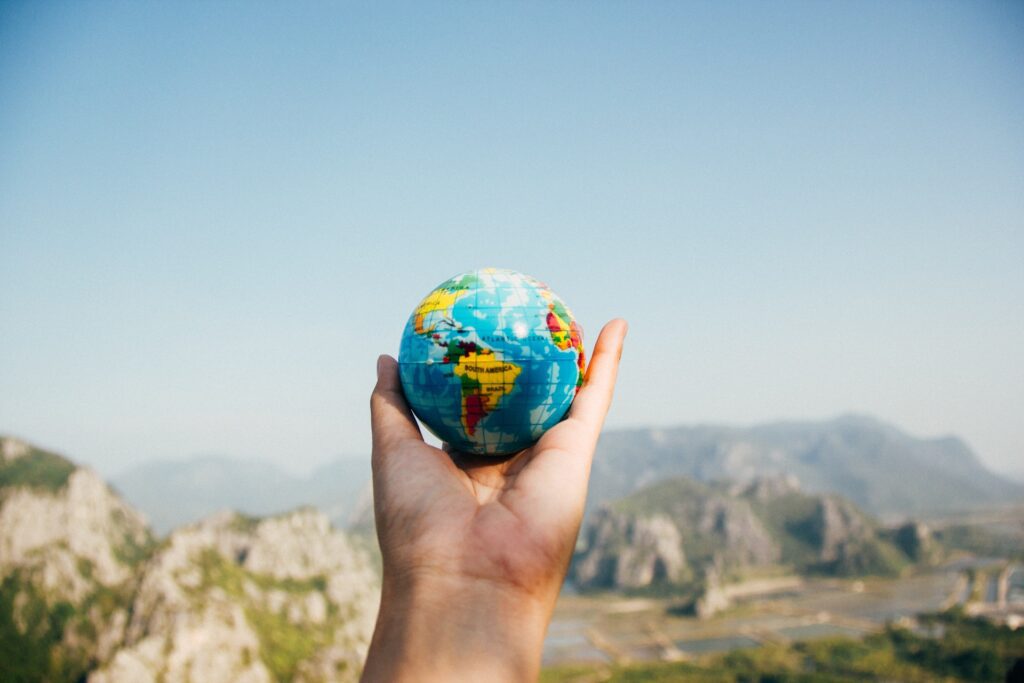 A hand holding a small globe