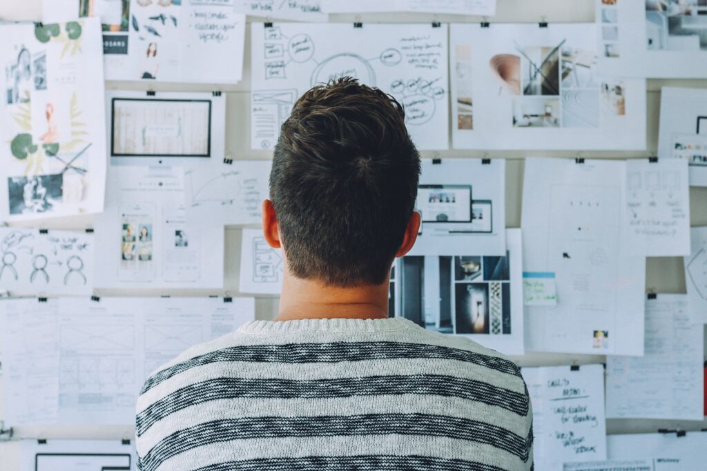 man looking at white board with post its