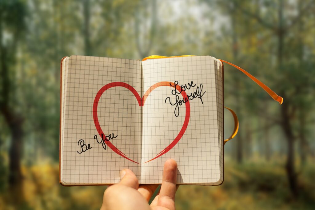 heart drawing in a book with hands holding