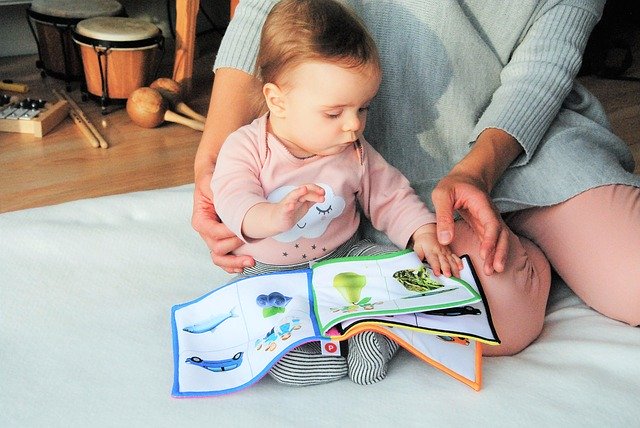 Mother and her baby playing with a soft book