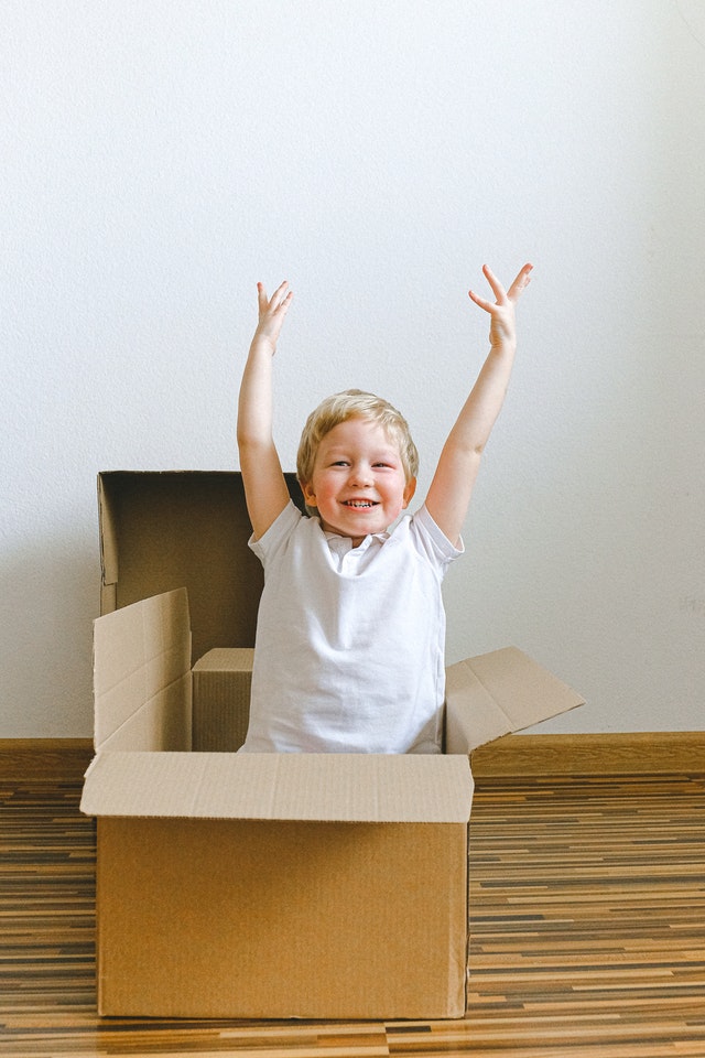 A boy playing with empty moving boxes to illustrate that such simple things can keep kids entertained during lockdown