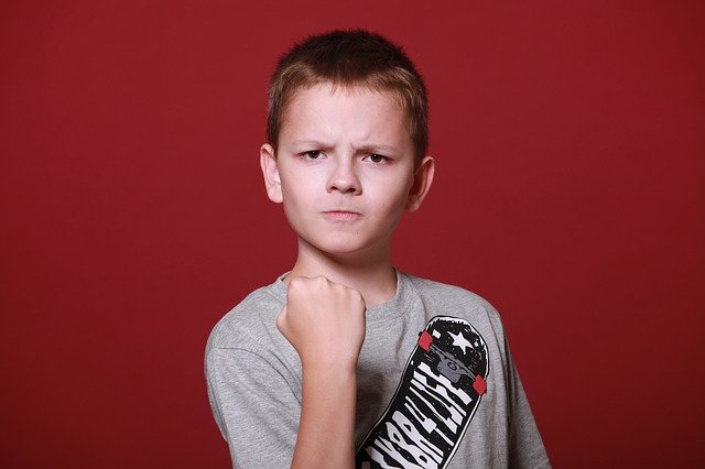 A child with an angry face making a fist