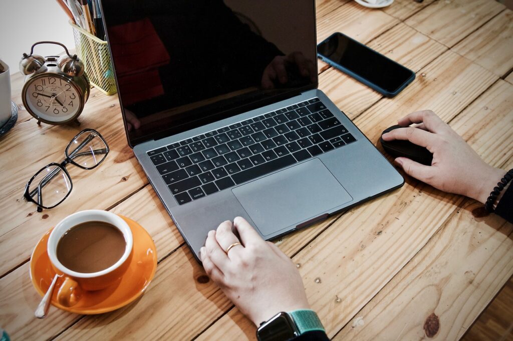 A person working on a laptop with a cup of coffee next to them.