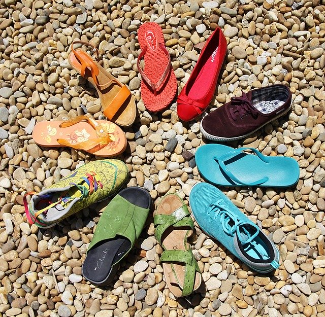 Various shoes placed in a circle on a pebble road.