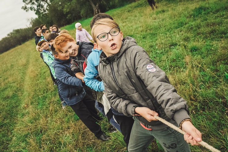 Kids playing tug of war in nature.