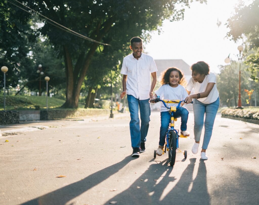 Mother and father teaching their daughter to drive a bicycle