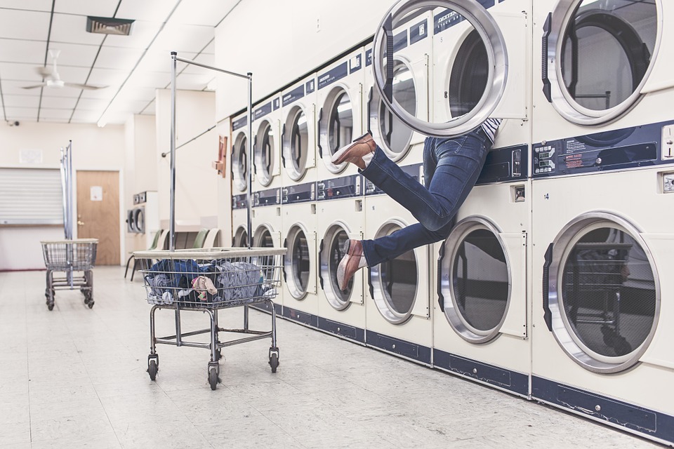 legs hanging out of a drier in a laundry mat.