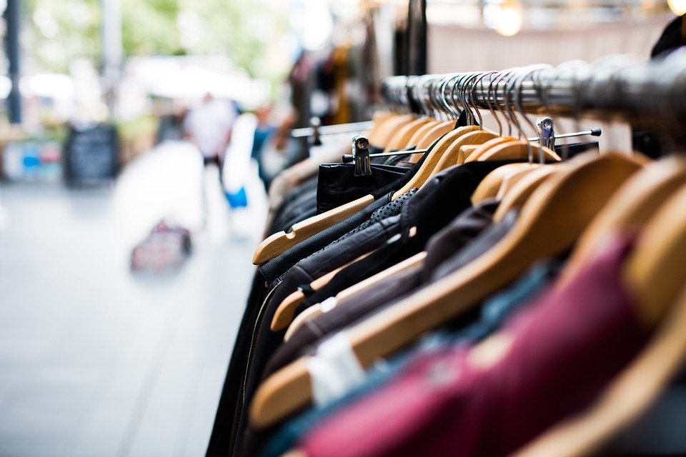 Clothing hanging on hangers in a store on the street.