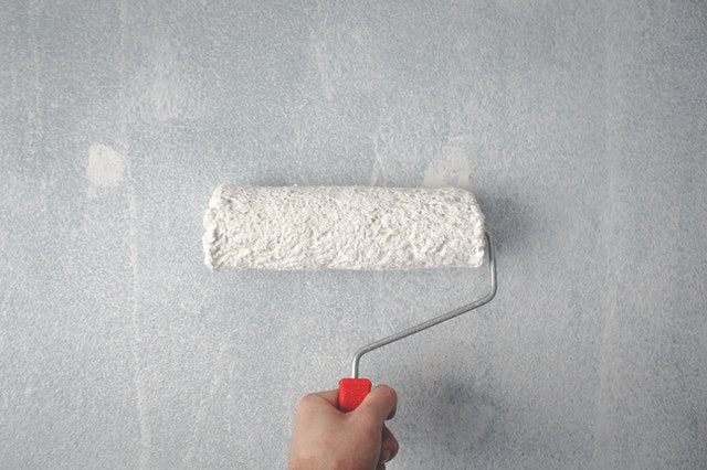 Hand holding a paint roller on the wall