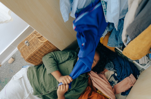 Girl lying down on a stack of clothes