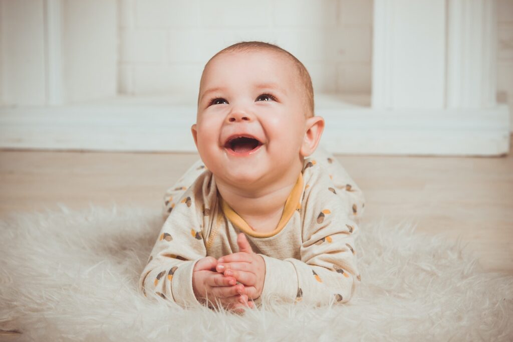 A baby lying on the floor and smiling