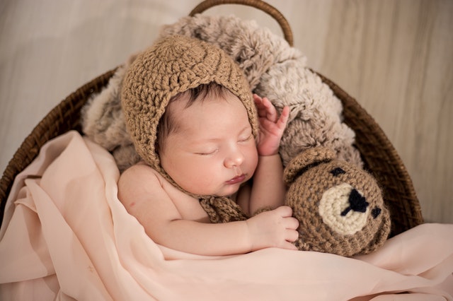 A baby wearing a brown knit cap while sleeping