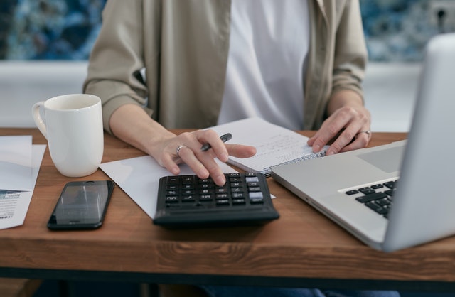 A woman sitting at a table, calculating how much money she will need for buying and selling a house at the same time.