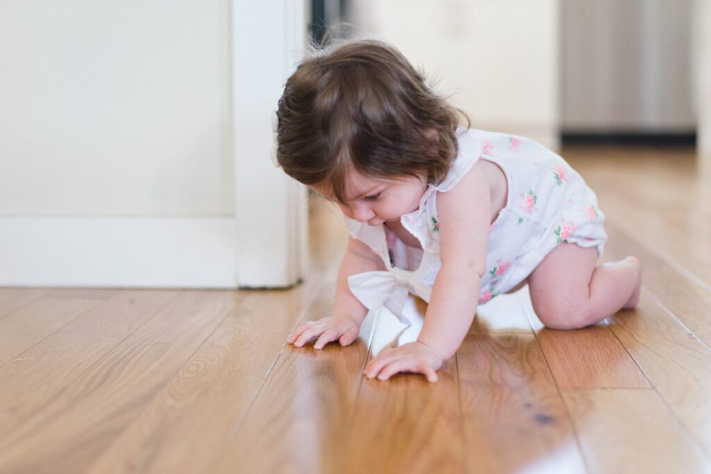 A baby girl crawling on the floor, symbolizing moving with a newborn