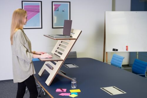 A woman following office space design trends and working on a standing desk. 