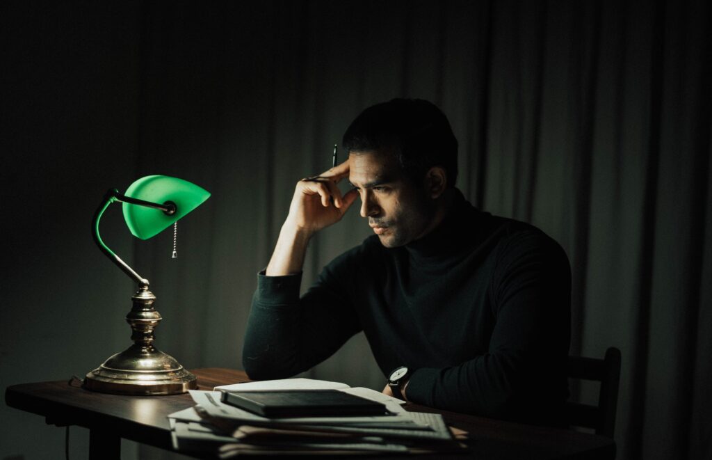 A man deep in thought while sitting at a desk with his hand on his forehead