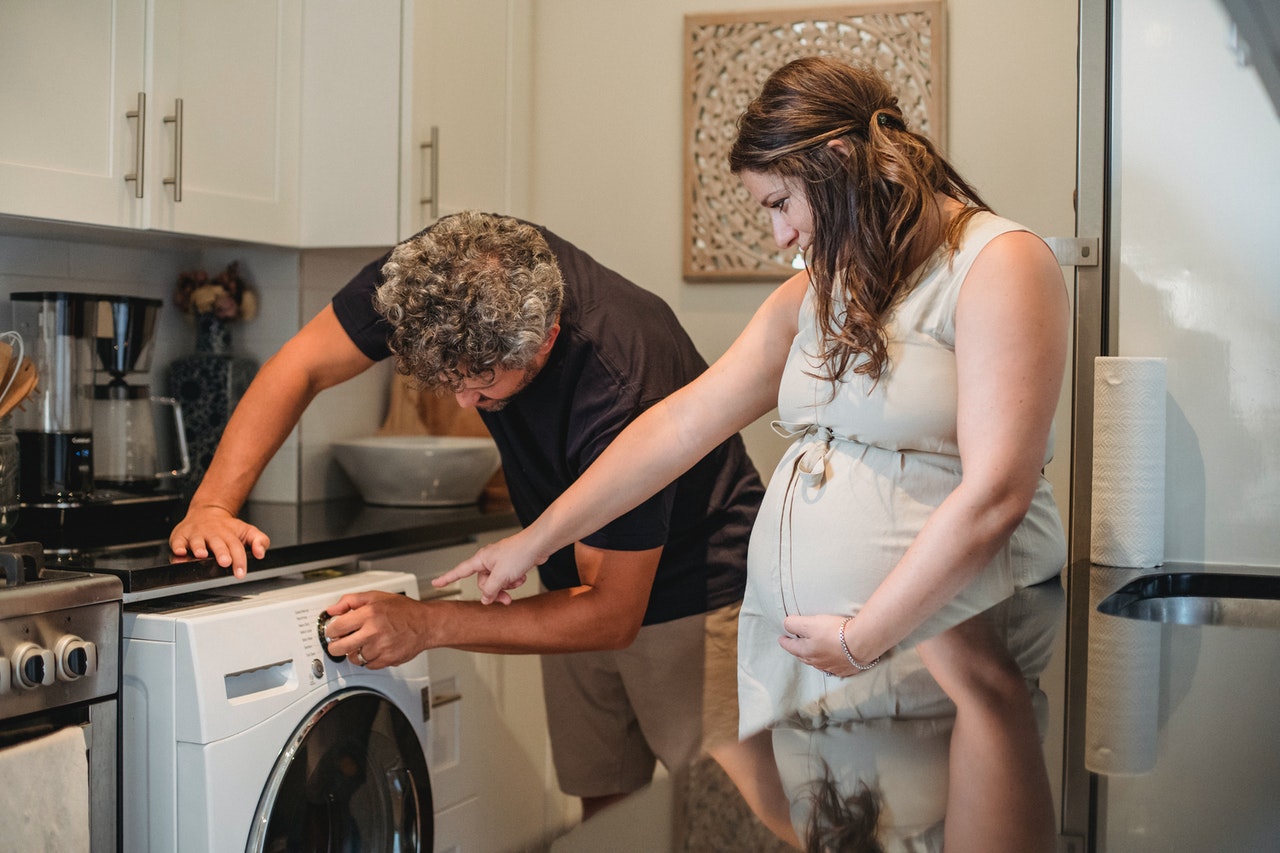 husband helping pregnant wife to do laundry