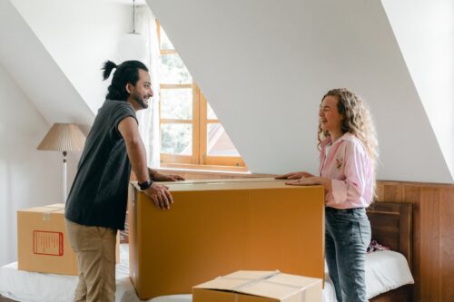 Happy couple holding a box with their furniture.