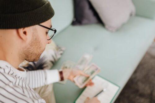 Man holding money in one hand and a pen in the other