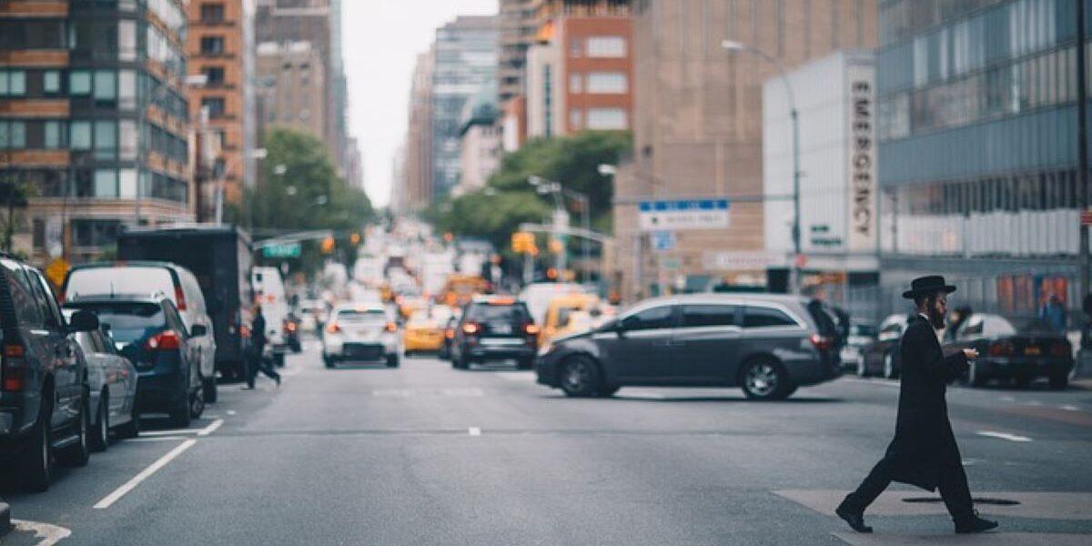 A man crossing the street in a busy intersection, highlighting urban life in one of NYC’s most walkable neighborhoods.