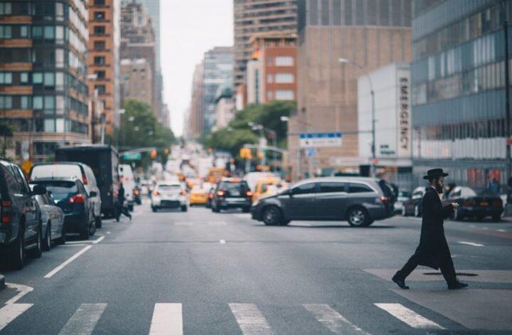 A man crossing the street in a busy intersection, highlighting urban life in one of NYC’s most walkable neighborhoods.