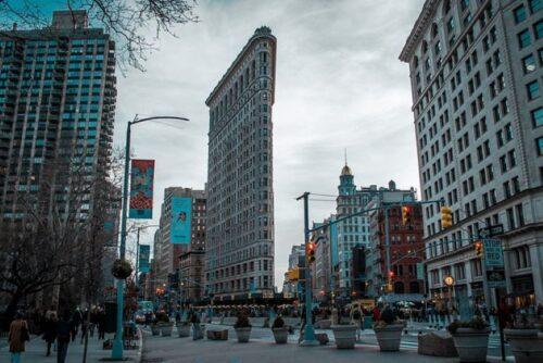 Flatiron Building in New York City surrounded by skyscrapers and a bustling street scene.