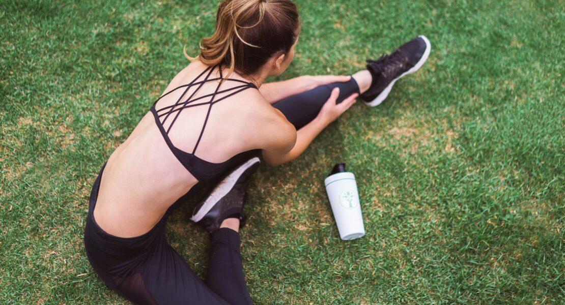 Person stretching on grass before exercise to support chronic pain relief through movement and physical activity.
