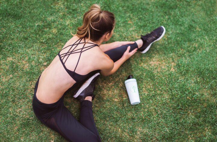 Person stretching on grass before exercise to support chronic pain relief through movement and physical activity.