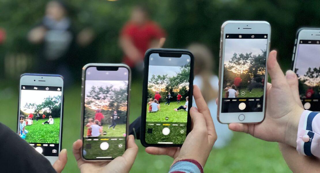 Several people using smartphones to photograph a group outdoors, illustrating teen phone use and screen time habits.