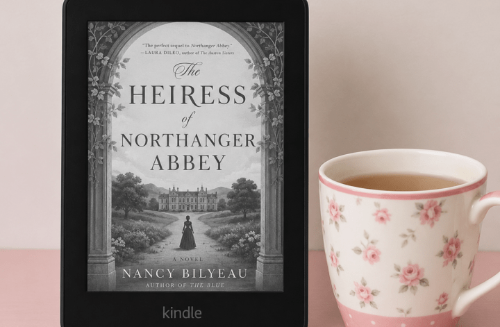Kindle displaying The Heiress of Northanger Abbey by Nancy Bilyeau beside a floral teacup on a pink tabletop.