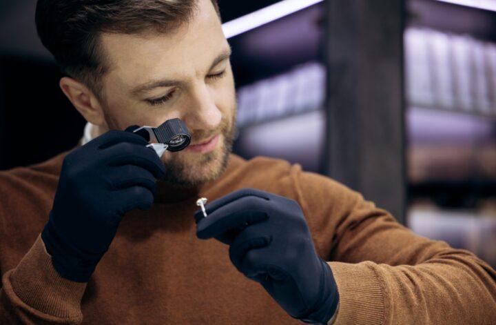 Jeweler inspecting a diamond ring with a loupe during a professional diamond appraisal.