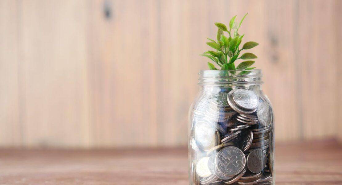 Glass jar filled with coins and a growing plant representing tax-efficient investing through ISAs and retirement accounts.