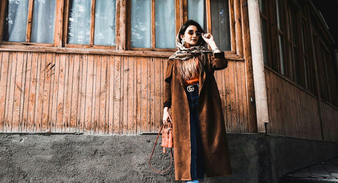 Woman wearing a long coat, scarf, jeans and boots in a winter style guide outfit.