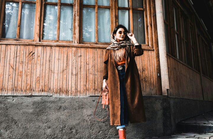 Woman wearing a long coat, scarf, jeans and boots in a winter style guide outfit.