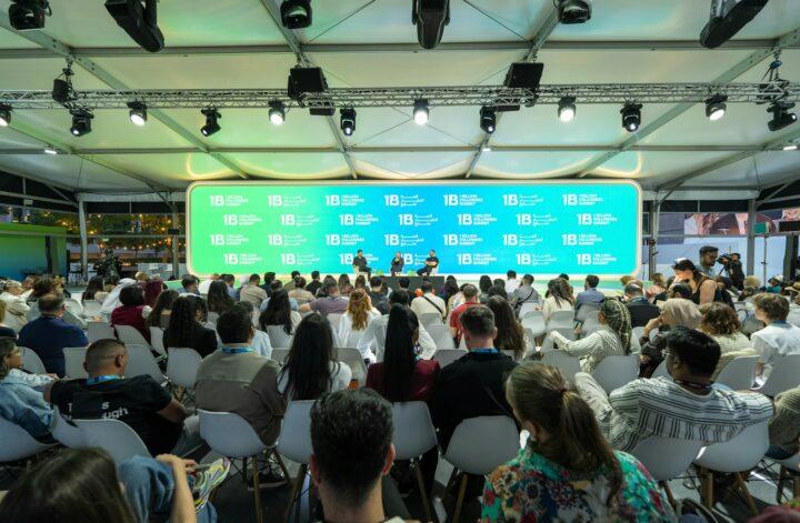 Audience attending a conference with branded event signage and stage presentation for event promotion.