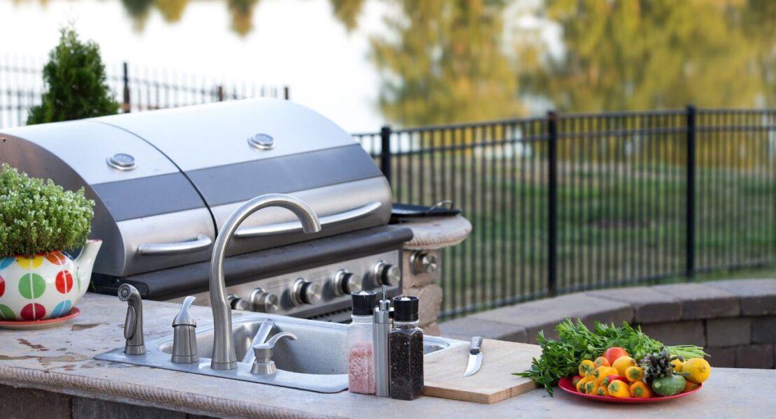 Outdoor kitchen with built-in grill, sink, prep counter, and fresh vegetables