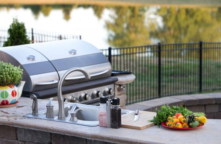 Outdoor kitchen with built-in grill, sink, prep counter, and fresh vegetables