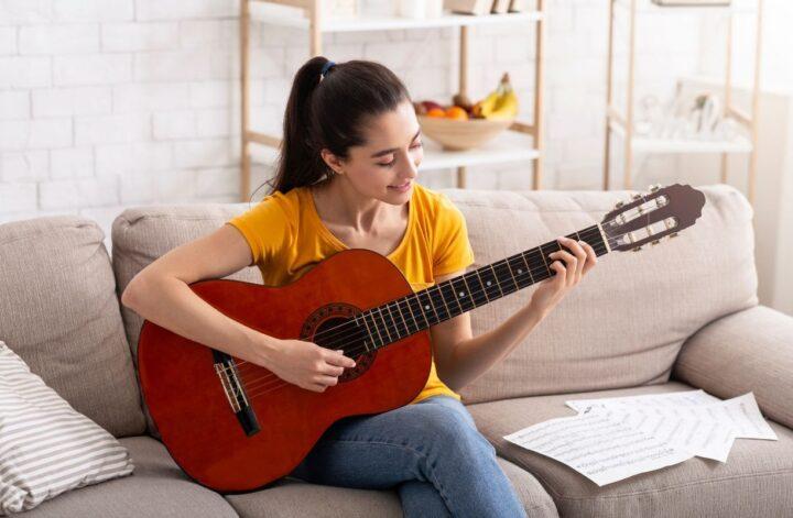Young adult playing acoustic guitar at home as a screen-free hobby.