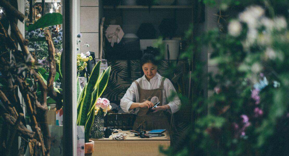 A small business owner working inside an established flower and plant shop.