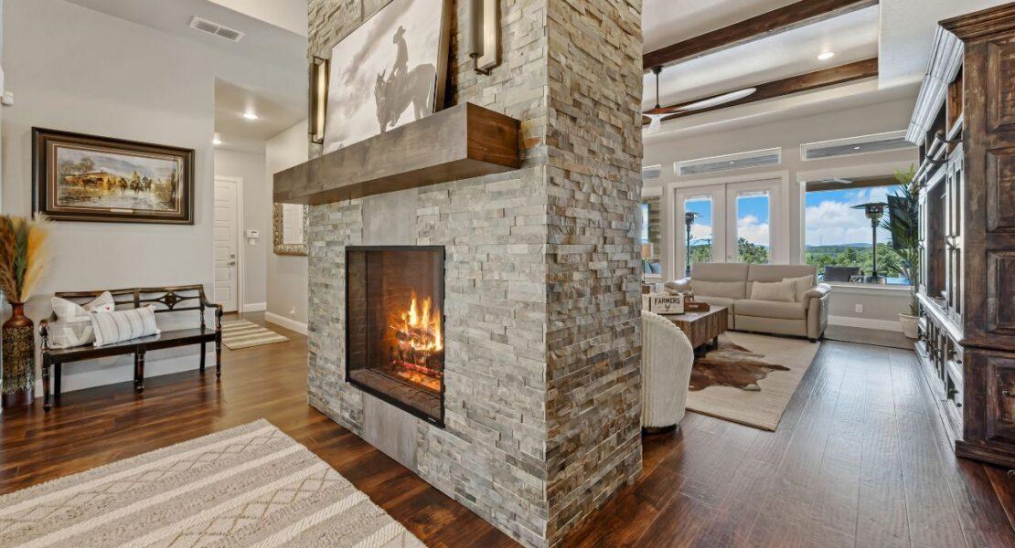 Stone fireplace feature wall with a wooden mantel, burning fire and warm lighting in a modern living room.