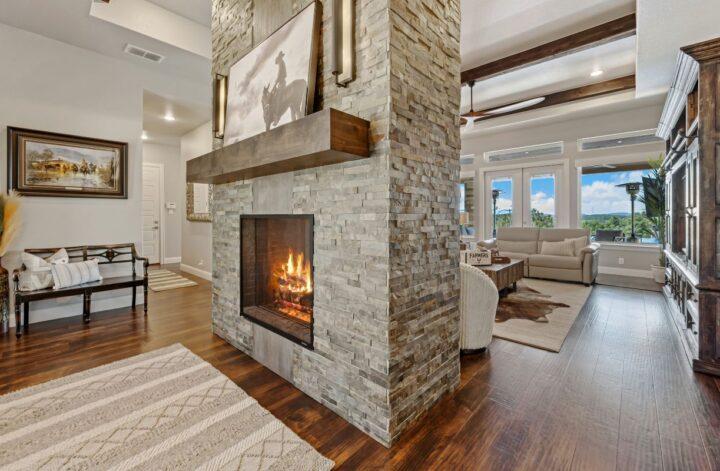 Stone fireplace feature wall with a wooden mantel, burning fire and warm lighting in a modern living room.